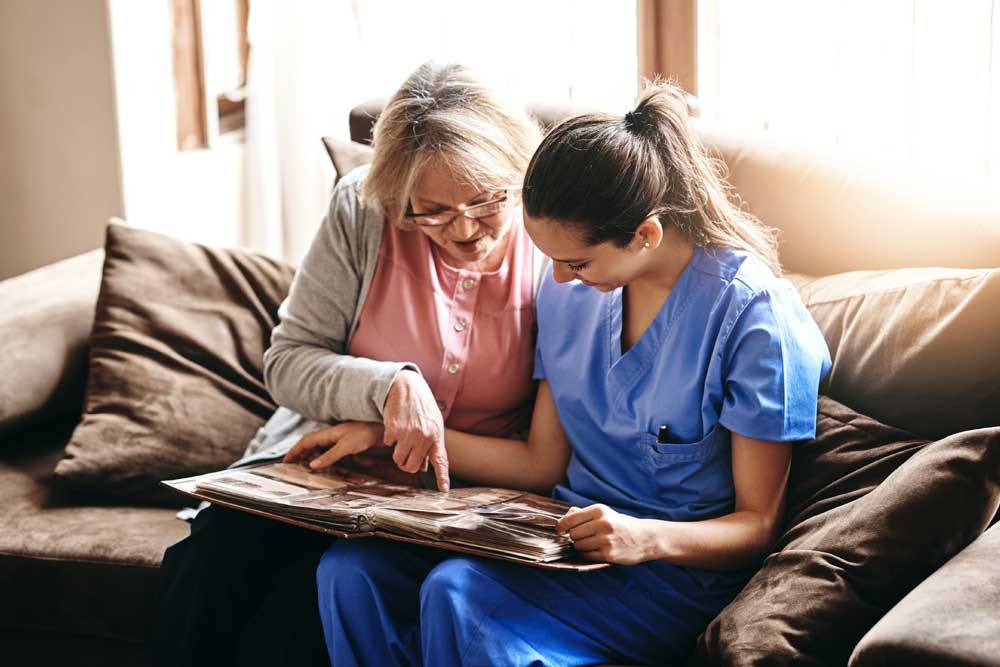 Resident and caregiver looking through a photo album and sharing memories at Charter Senior Living of Jefferson City, TN.