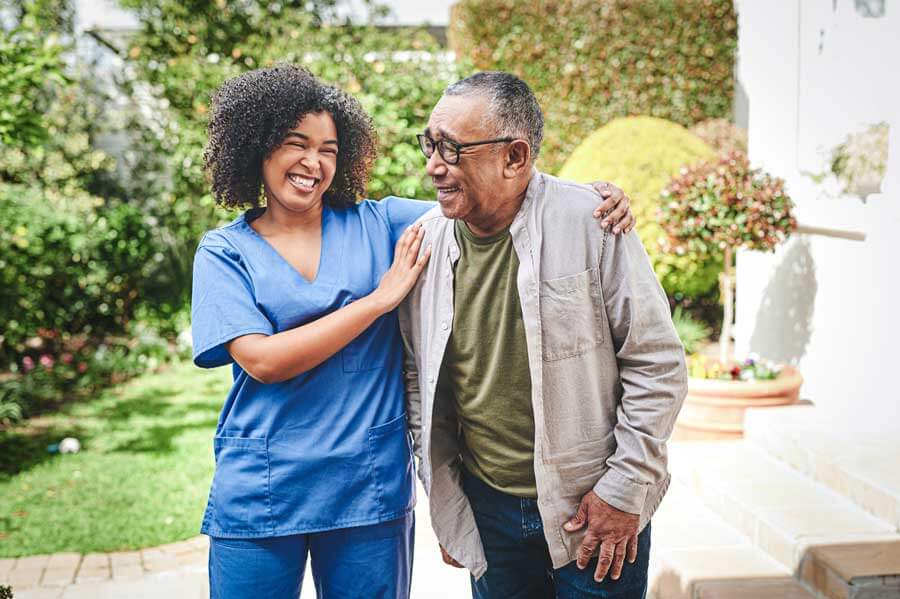 Caregiver walking outside with a resident, both smiling and enjoying a sunny day in Jefferson City, TN.