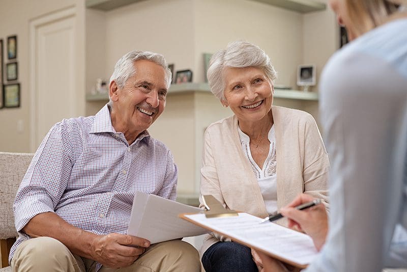 Smiling couple reviewing documents with a staff member at Charter Senior Living of Jefferson City, TN.